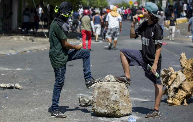 Unos jóvenes hacen un alto en las protestas para refrescarse comiendo helado. FOTO/EFE