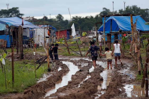 Niños recorren un camino lodoso en el terreno 