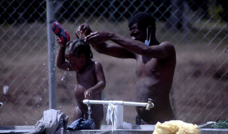 Un padre migrante baña a su hijo en el albergue de San Vicente, provincia de Darién. Víctor Arosemena