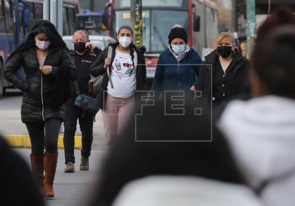 Personas caminan protegidas con mascarillas por una calle en Santiago de Chile. Foto: EFE