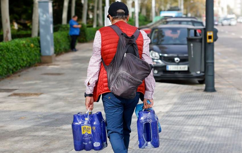 Un hombre carga con varias botellas de agua en Valencia. Foto: EFE